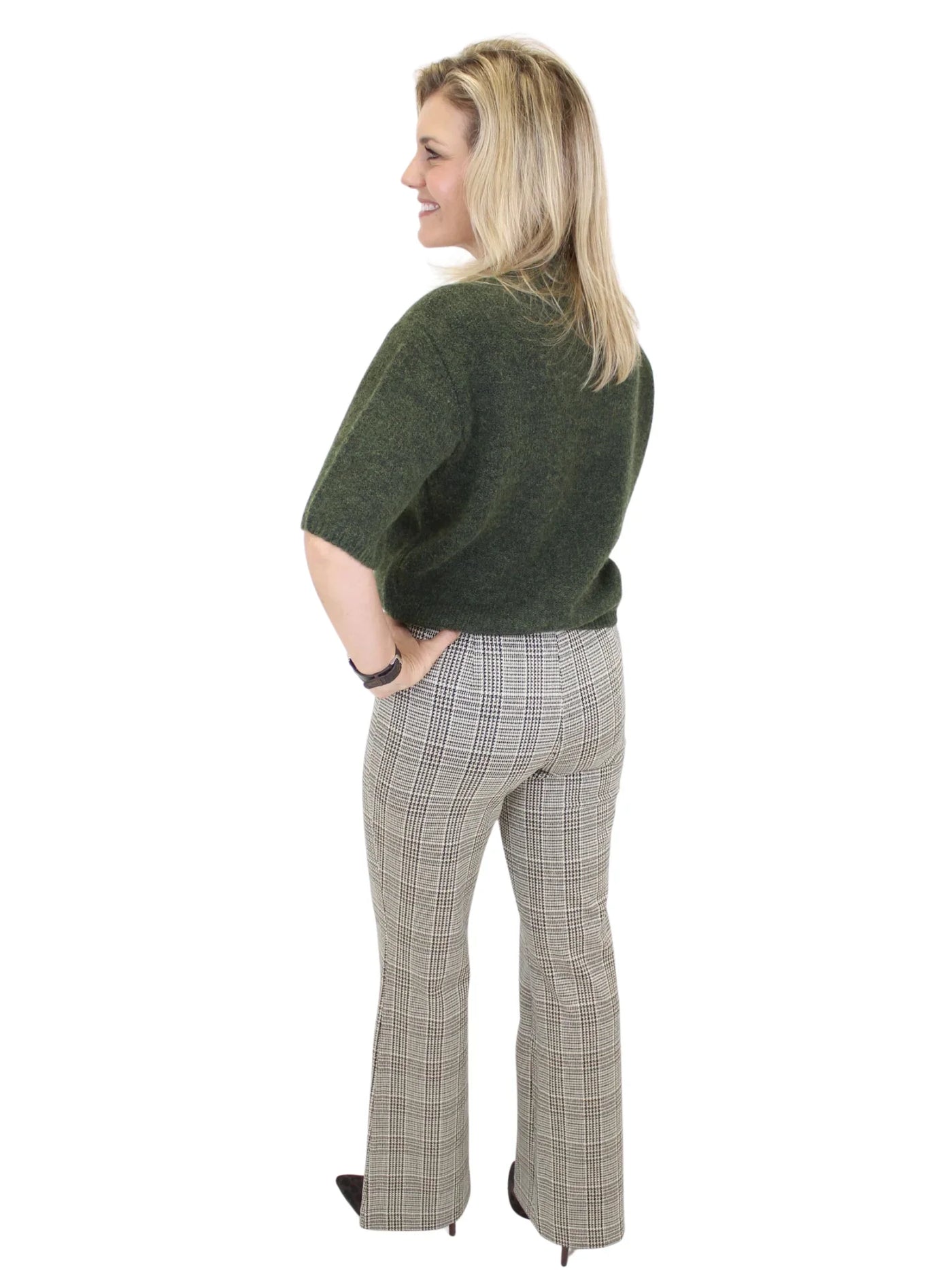 Woman wearing a green sweater and plaid pants on a white background