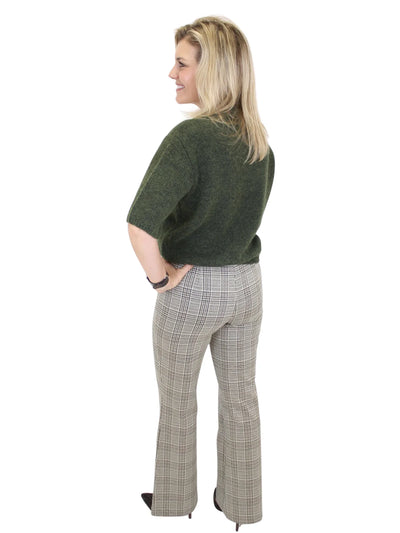 Woman wearing a green sweater and plaid pants on a white background