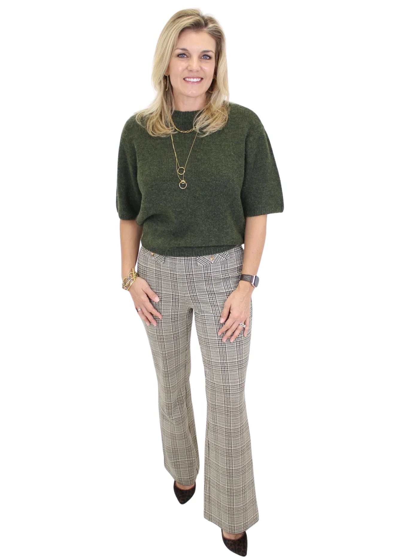 Woman wearing a green sweater and plaid pants on a white background