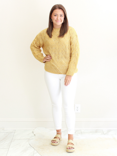 Gold Cable Knit Sweater front view with white jeans.