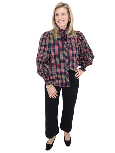 Woman wearing a plaid shirt and black pants on a white background
