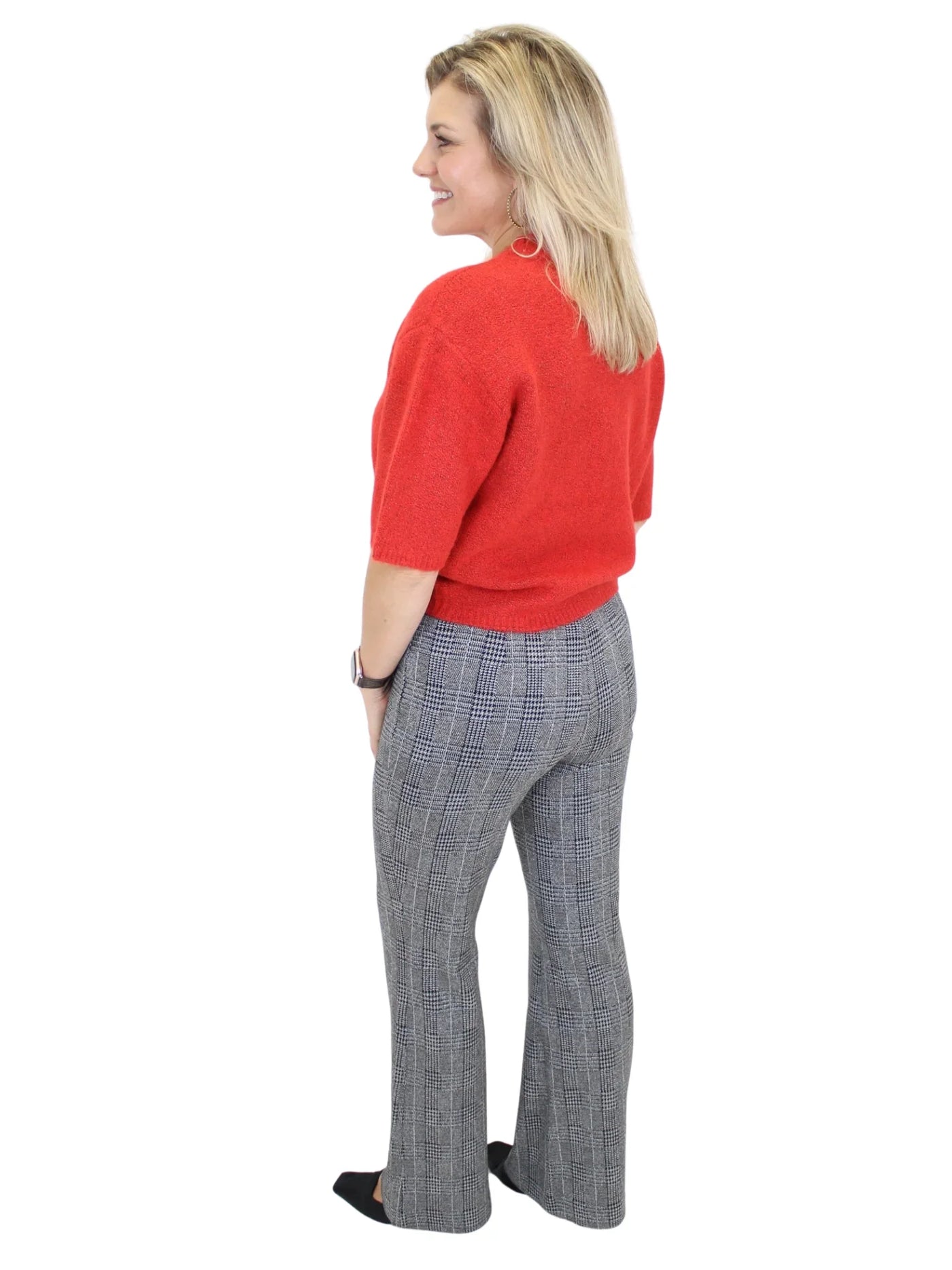 Woman wearing a red sweater and gray checkered pants on a white background