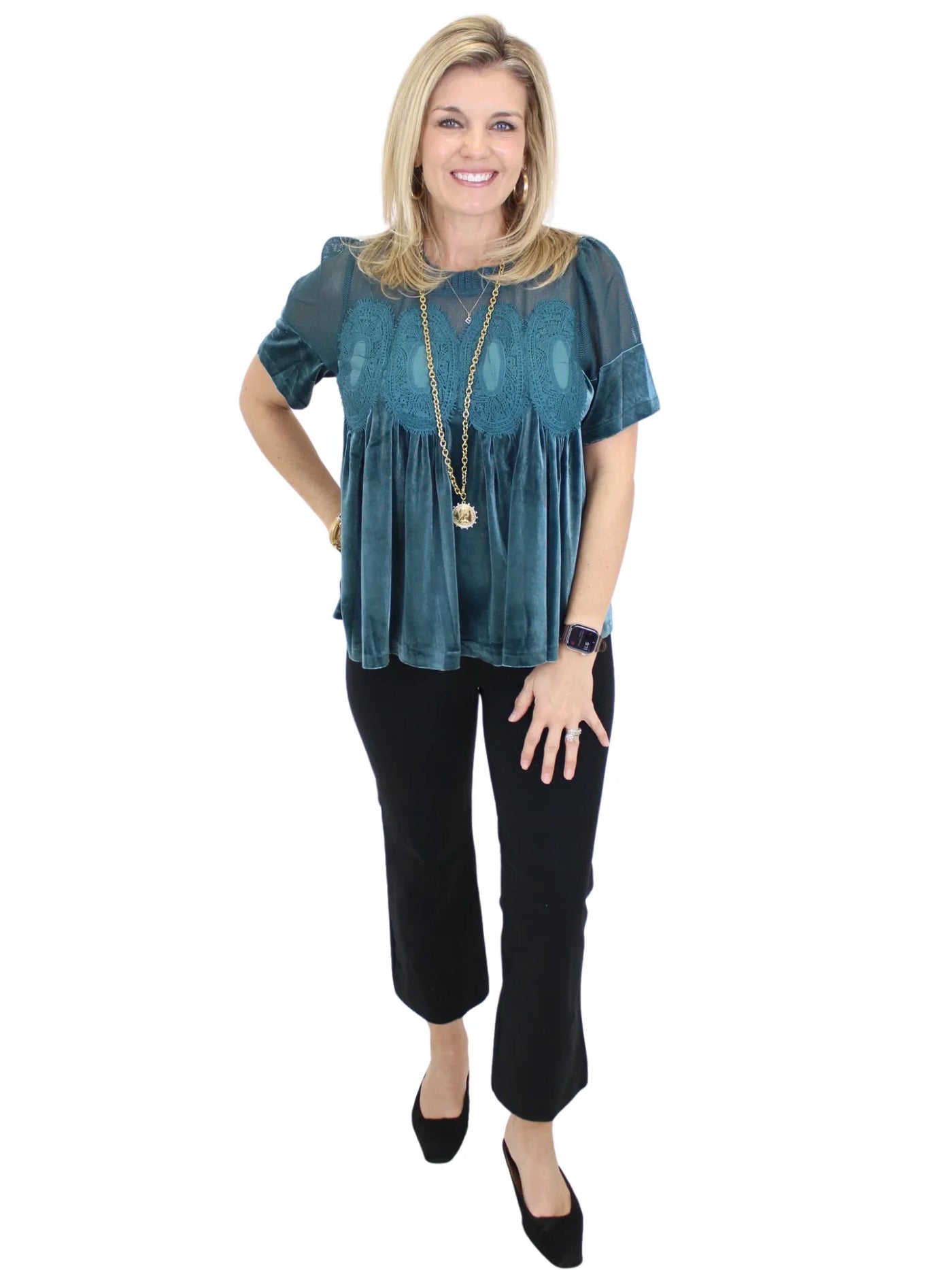 Woman wearing a teal top and black pants on a white background