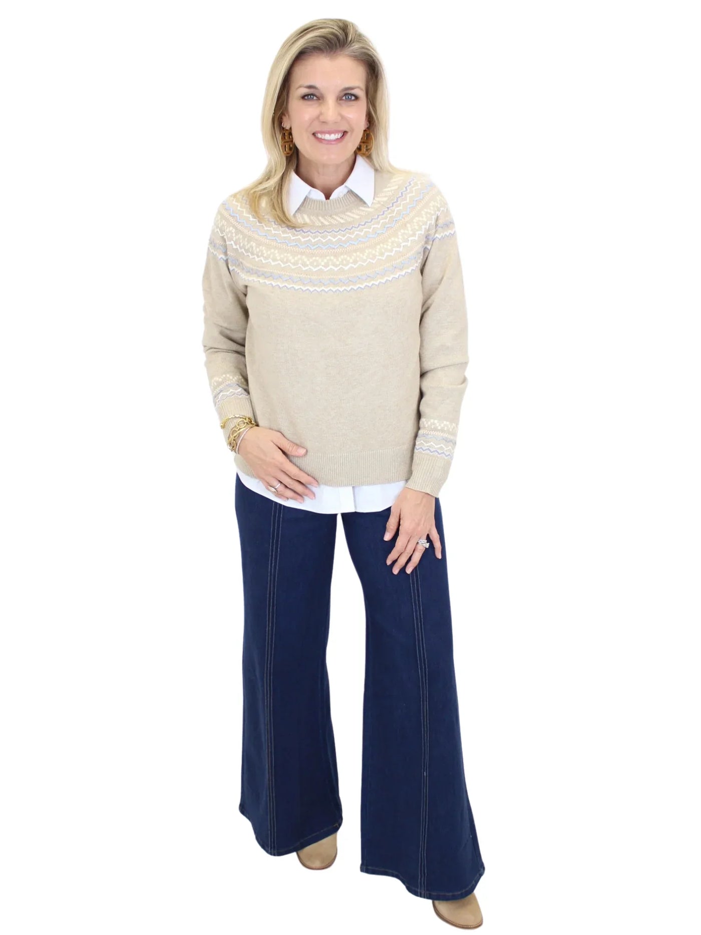 Woman wearing a beige sweater and blue pants on a white background