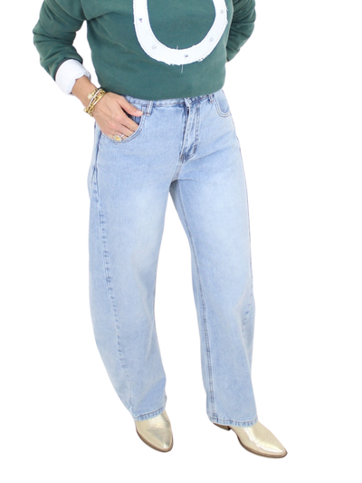 Person wearing a green sweater with a large white letter 'U' and light blue jeans on a white background