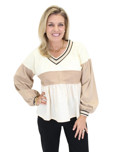 Woman wearing a cream and beige long-sleeve top on a white background
