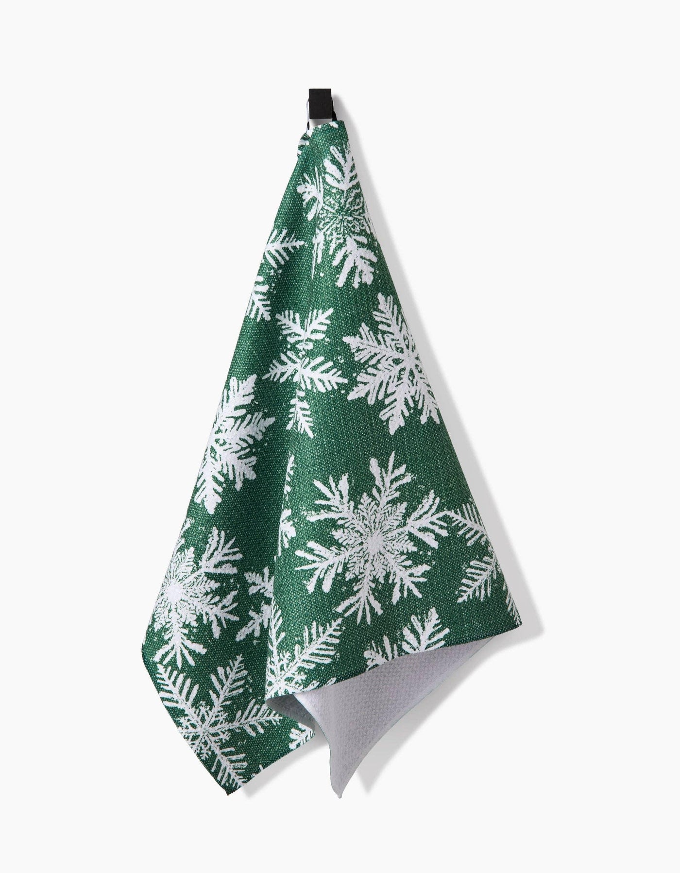 Green towel with white snowflake pattern hanging on a white background