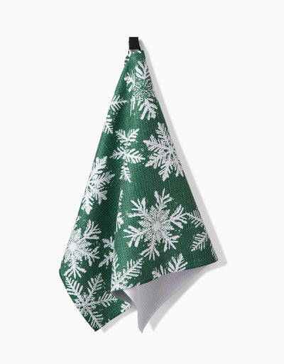 Green towel with white snowflake pattern hanging on a white background