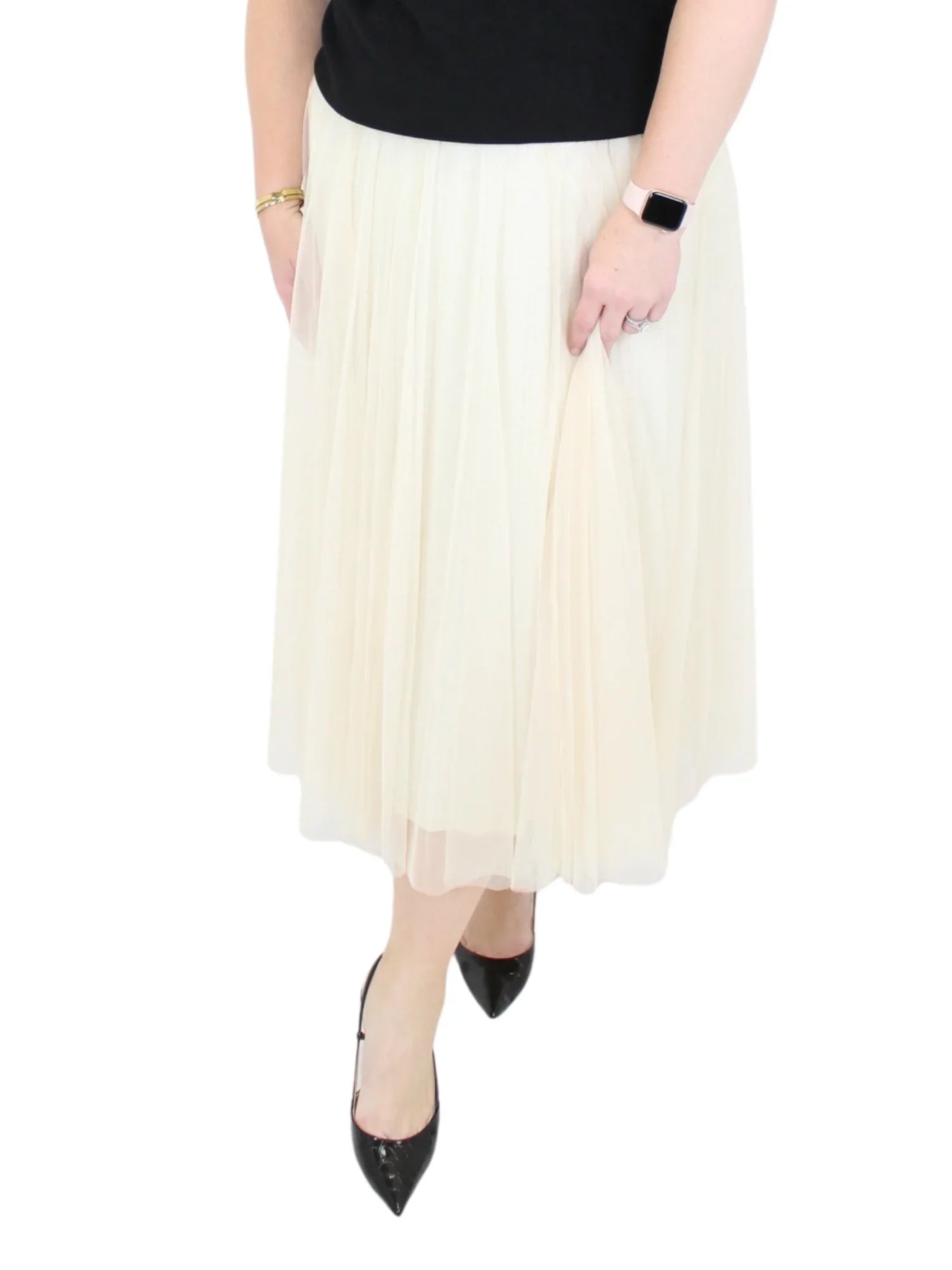 Person wearing a white pleated skirt with black shoes on a white background