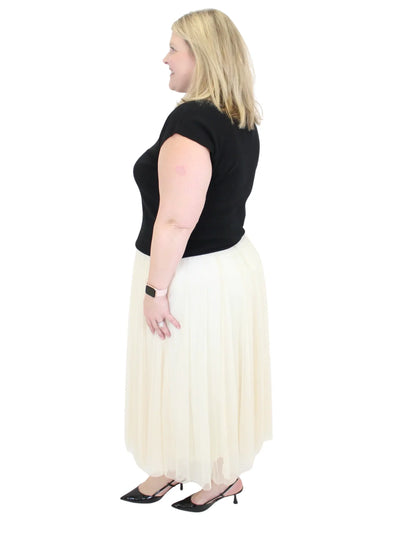 Woman wearing a black top and cream skirt on a white background
