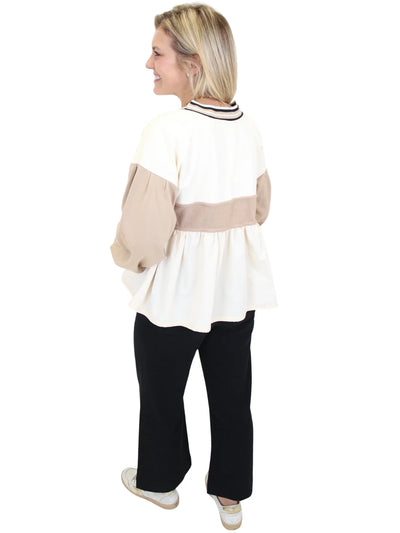 Woman wearing a white and beige top with black pants on a white background