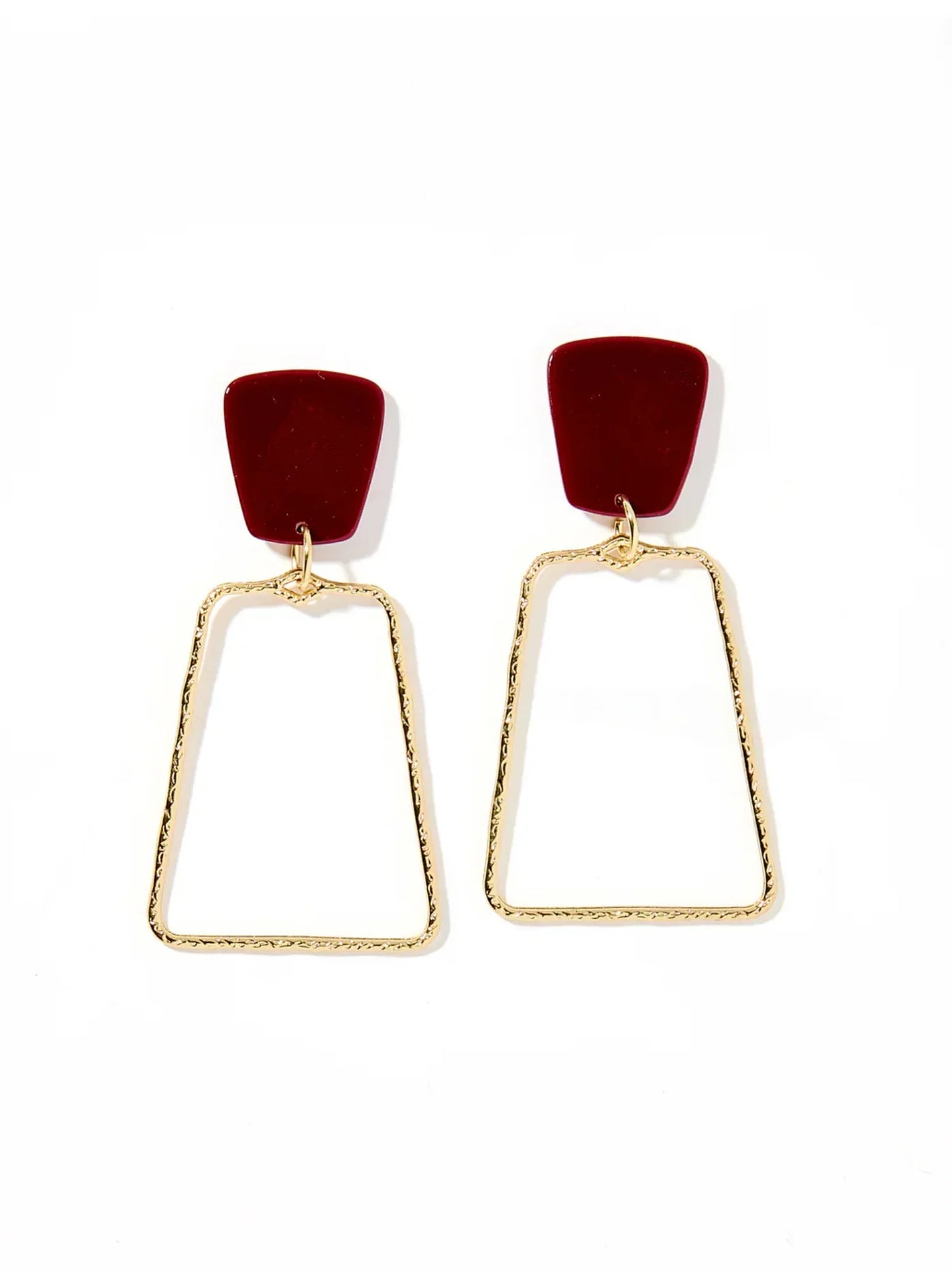 Pair of earrings with red tops and gold frames on a white background