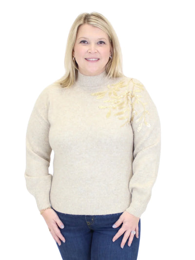 Woman wearing a cream sweater with a subtle pattern on a white background