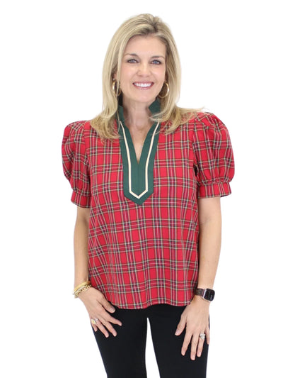 Woman wearing a red plaid blouse with green trim on a white background