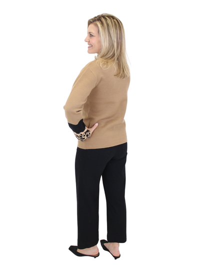 Woman wearing a beige sweater and black pants on a white background