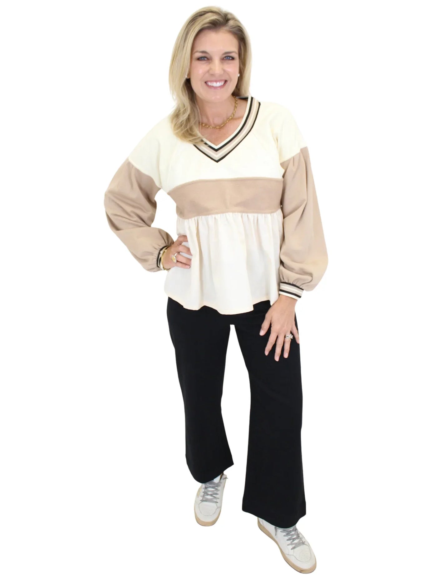 Woman wearing a beige and white top with black pants on a white background
