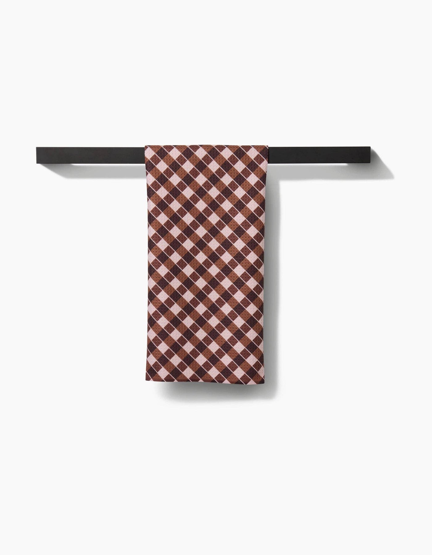 Checkered brown tea towel hanging on a black metal rack against a white background
