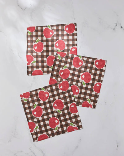 Three checkered dishcloths with red apple pattern on a white marble surface