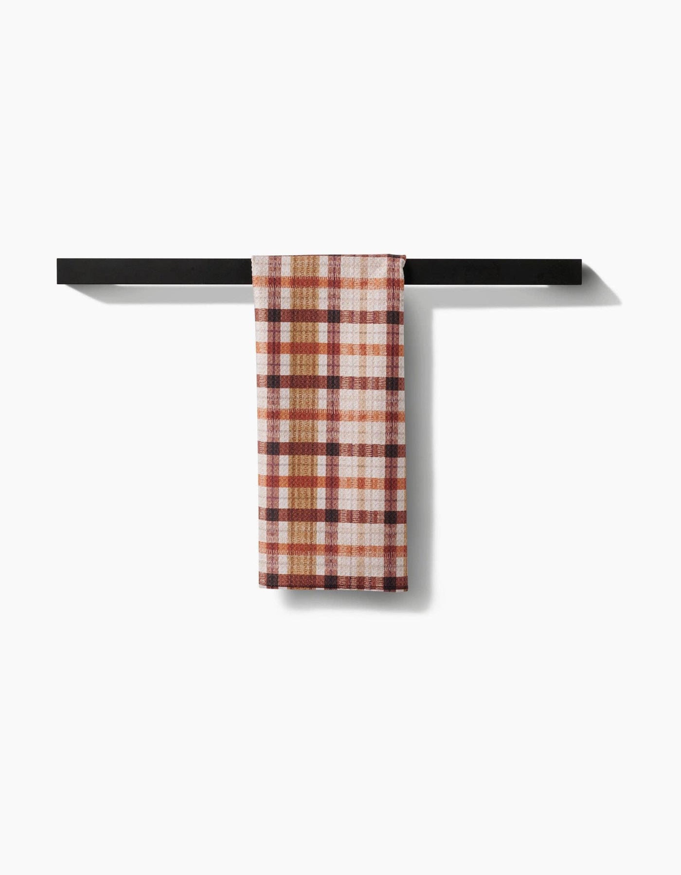 Plaid towel hanging on a black metal towel rack against a white background