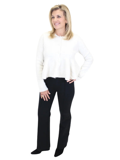 Woman wearing a white sweater and black pants on a white background
