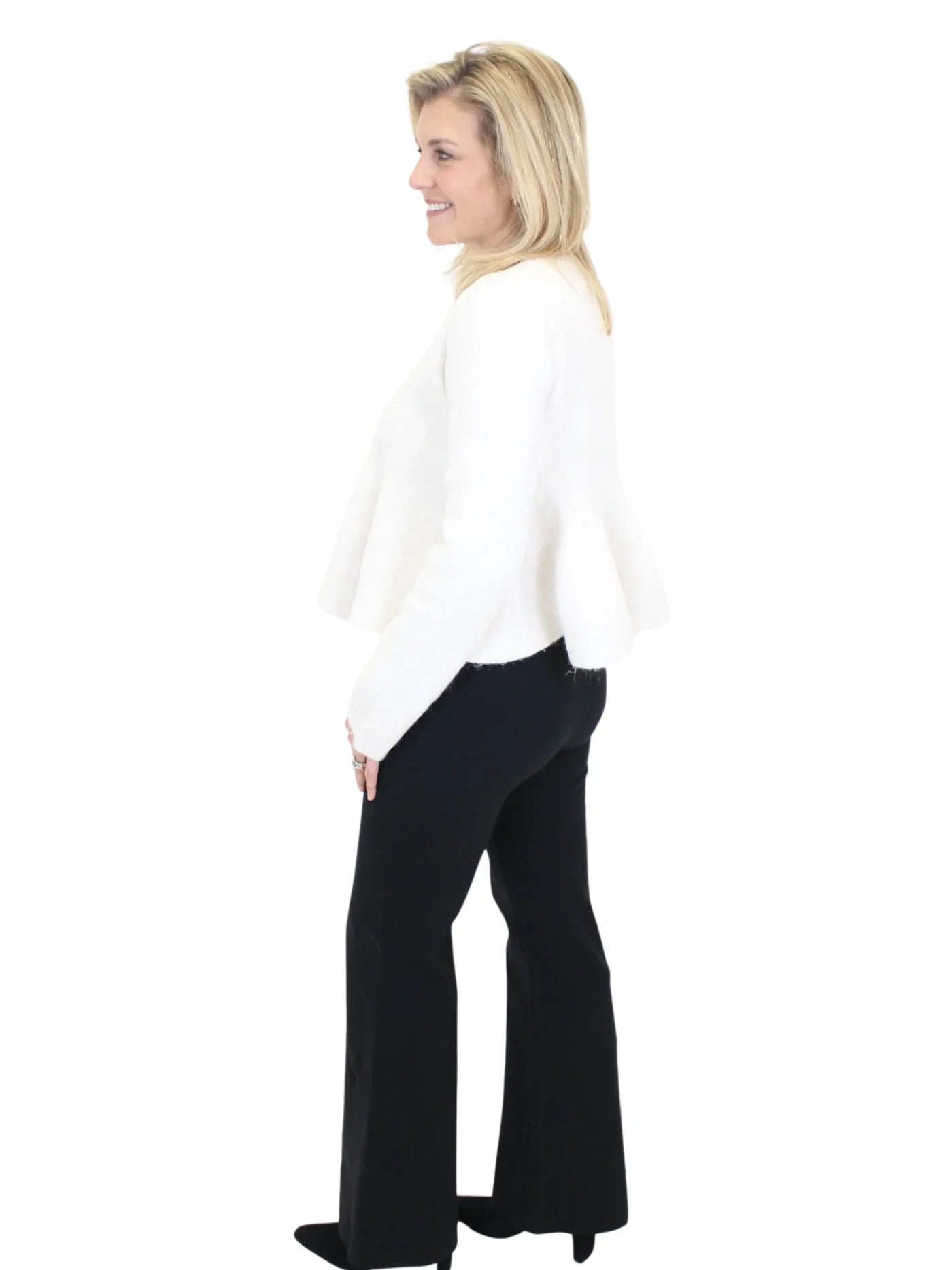 Woman wearing a white sweater and black pants on a white background
