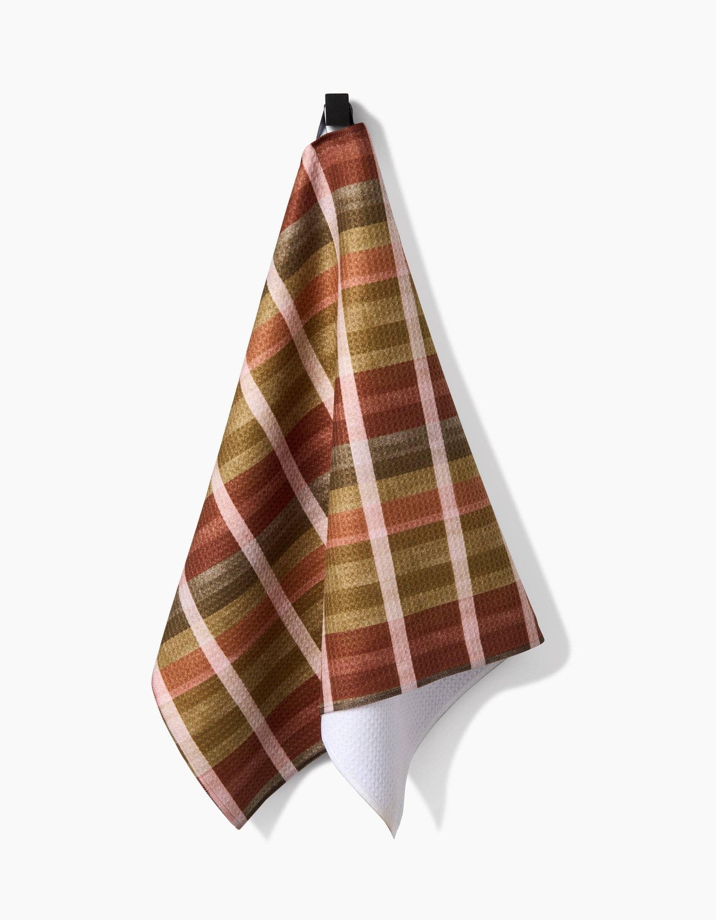 Plaid tea towel with autumnal colors hanging on white background
