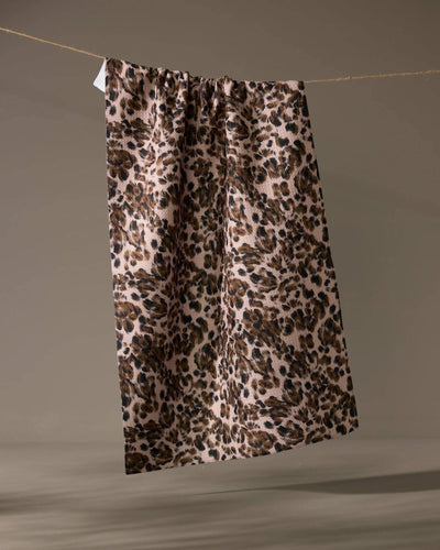Leopard print tea towel hanging on a line against a taupe background