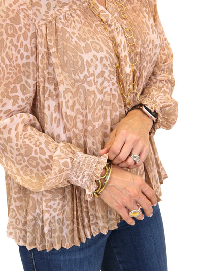 Close-up of a person wearing a leopard print blouse with long sleeves and blue jeans.