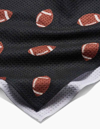 Black tea towel with brown football pattern on white background, closeup.