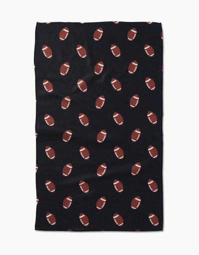 Black tea towel with brown football pattern on a white background.