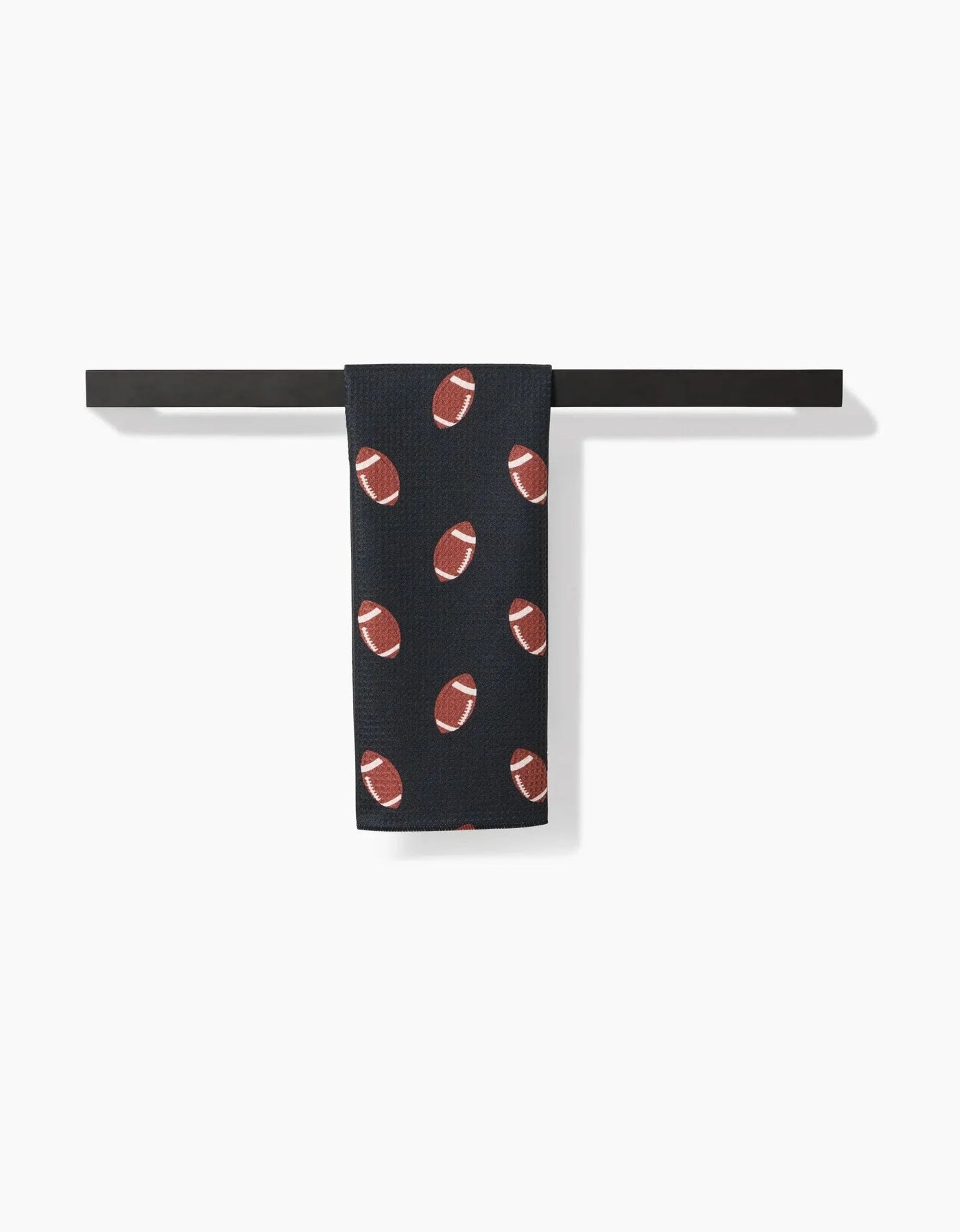 Black towel with brown football pattern hanging on a black rack against a white background