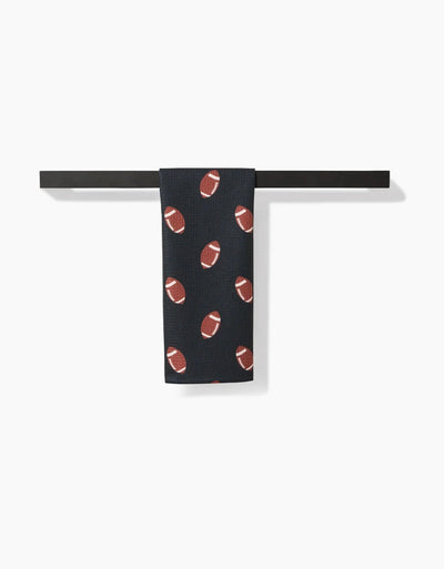 Black towel with brown football pattern hanging on a black rack against a white background