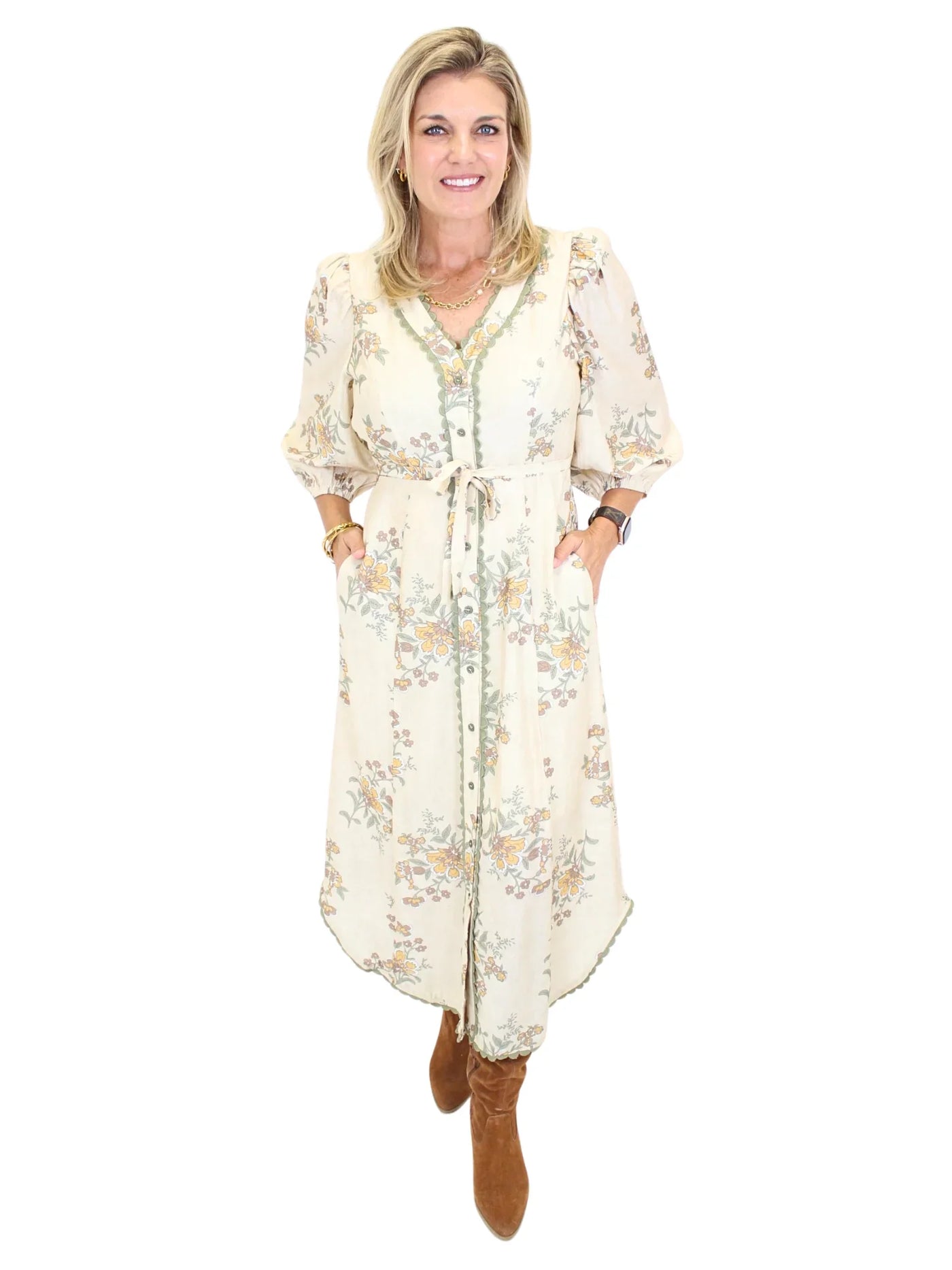 Woman wearing a long cream floral dress on a white background, front.