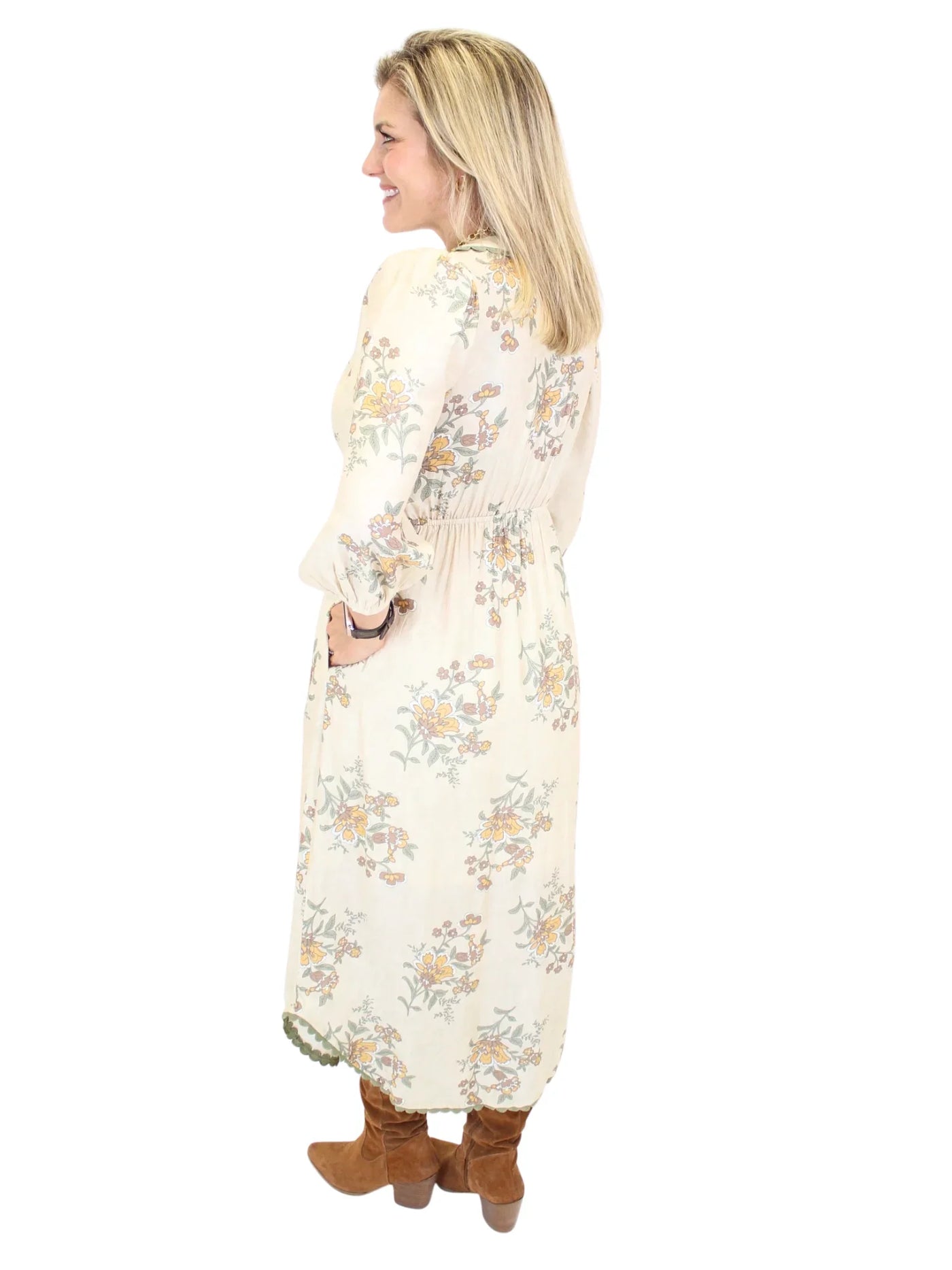 Woman wearing a long cream floral dress on a white background, back.