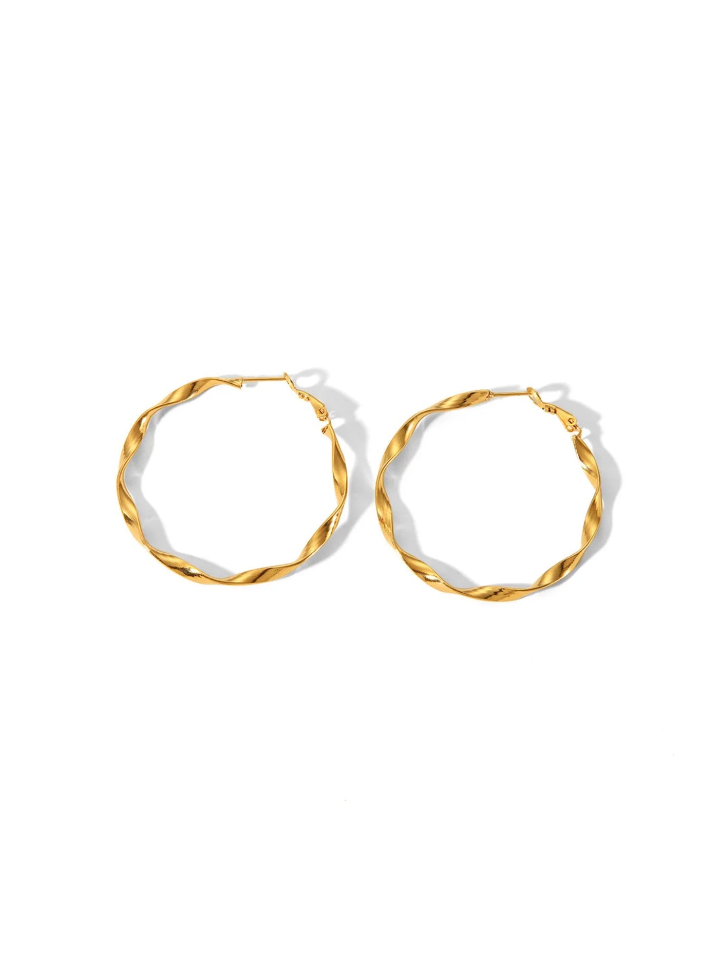 Twisted gold brushed hoops on white background.