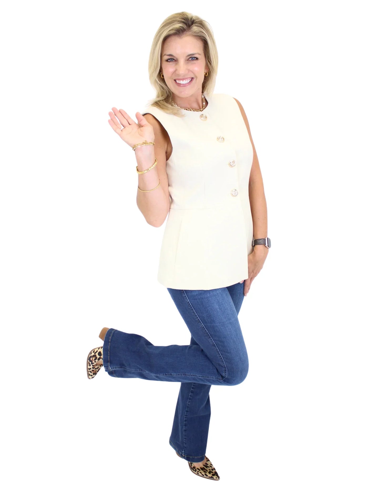 Woman wearing a sleeveless cream top and blue jeans on a white background