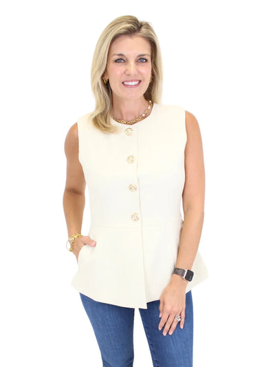 Closeup of woman wearing a cream sleeveless vest top and blue jeans on a white background