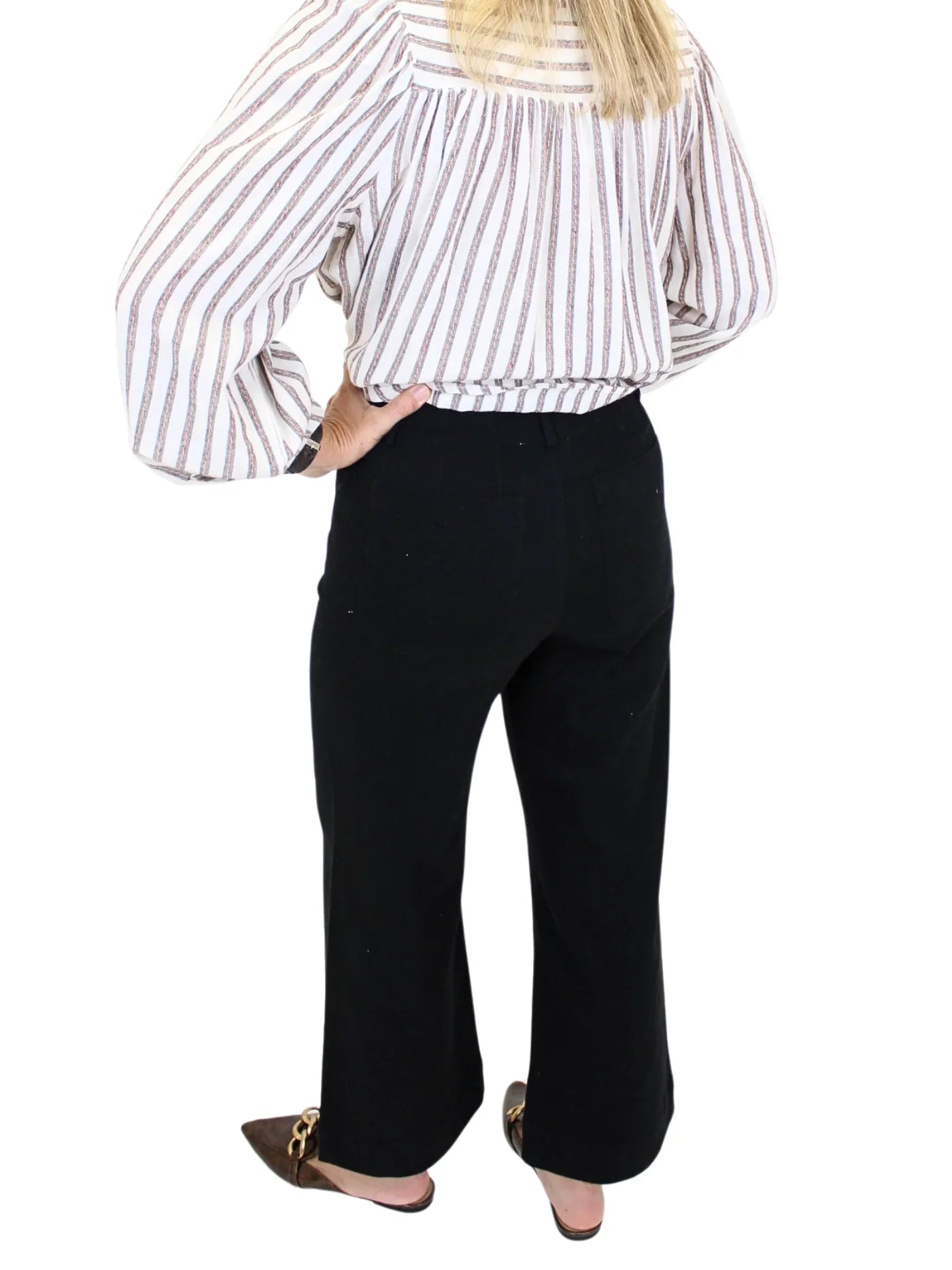 Woman wearing a striped shirt and black pants on a white background, closeup back.