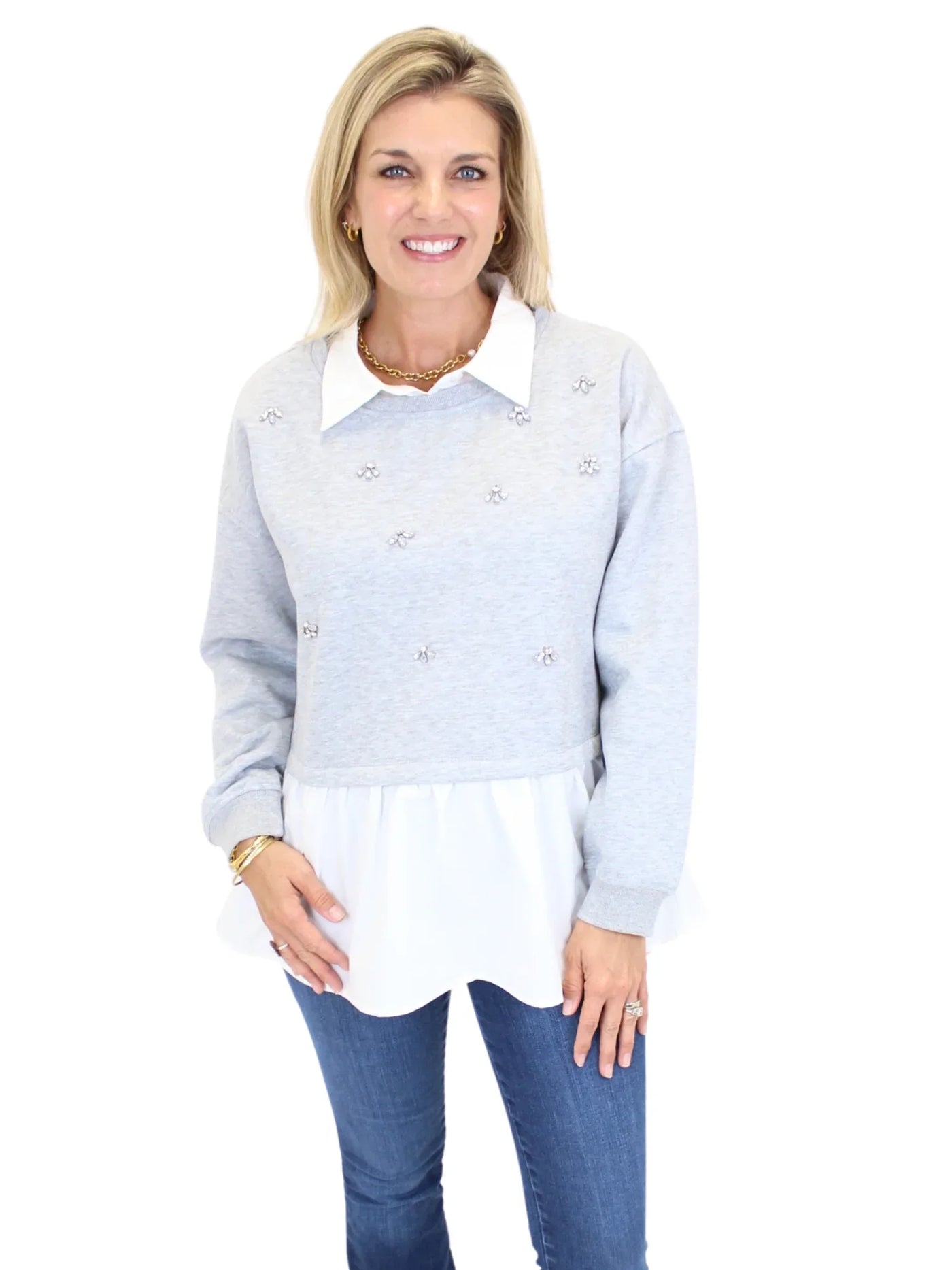 Woman wearing grey sweater with white collar and embellishments on white background, closeup