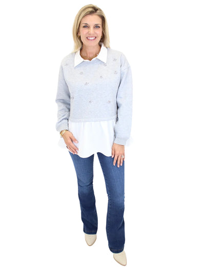 Woman wearing grey sweater with white collar and embellishments on white background, front