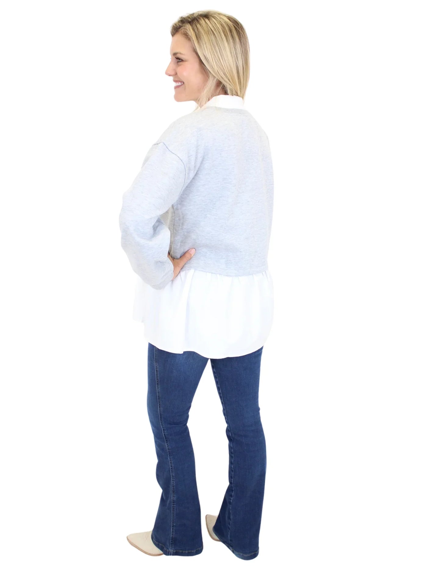 Woman wearing grey sweater with white collar and embellishments on white background, back