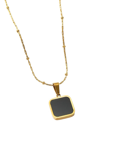 Gold necklace with a black square pendant on a white background