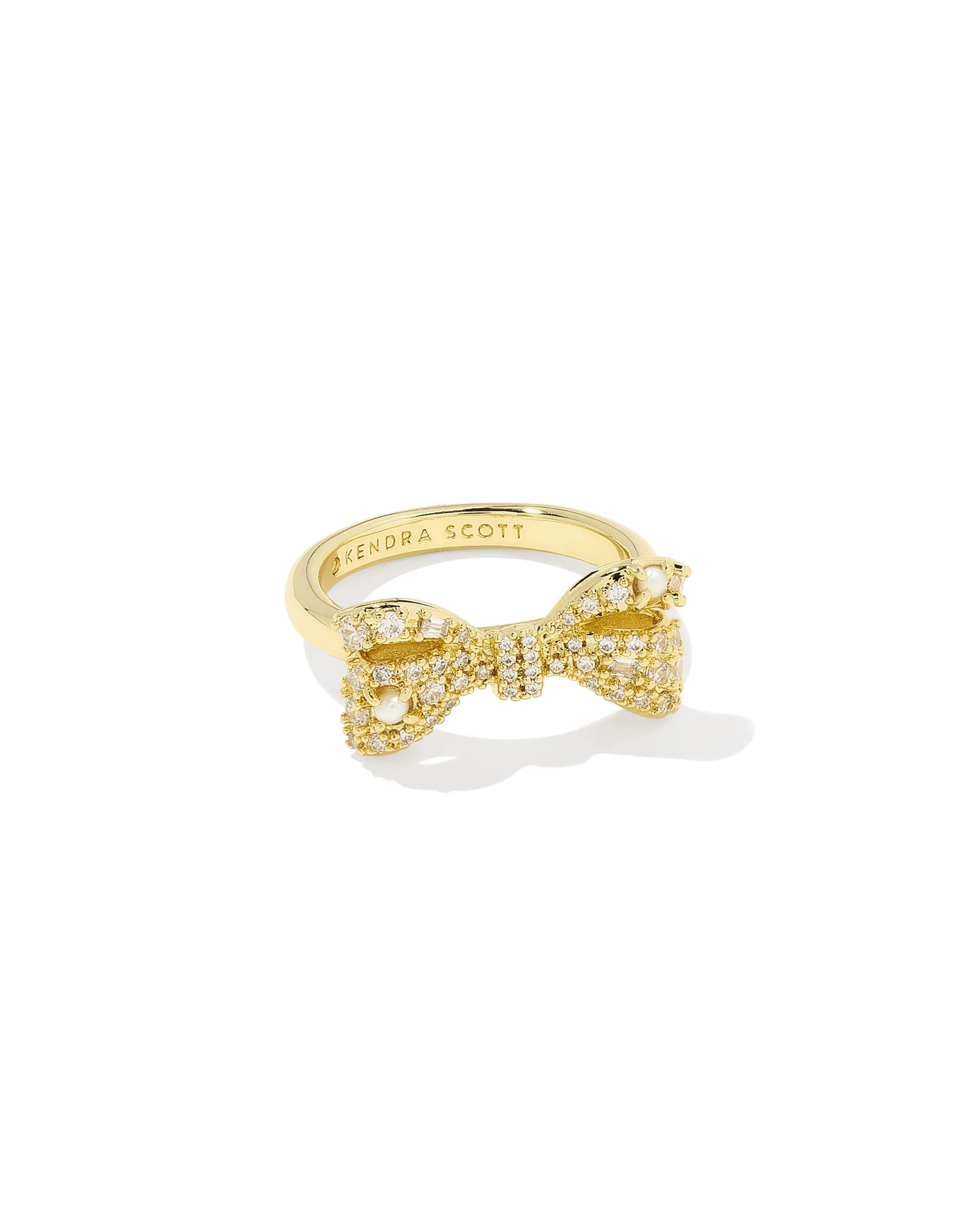 Gold bow ring with pearls and cubic zirconia on white background.