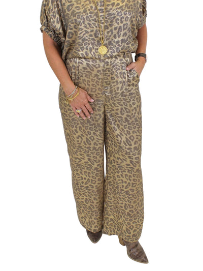 Model wearing metallic leopard print pants on white background, closeup front.