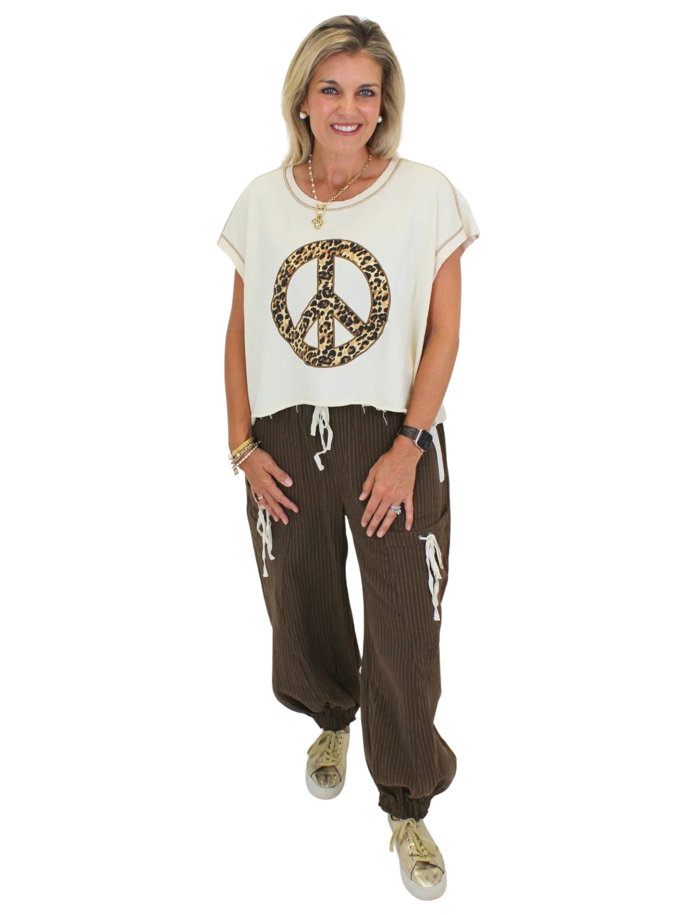 Model wearing cheetah print peace sign top with brown striped joggers on white background, front.
