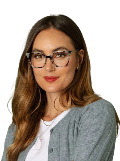 Woman wearing tortoiseshell rounded square glasses and a gray cardigan on a white background.