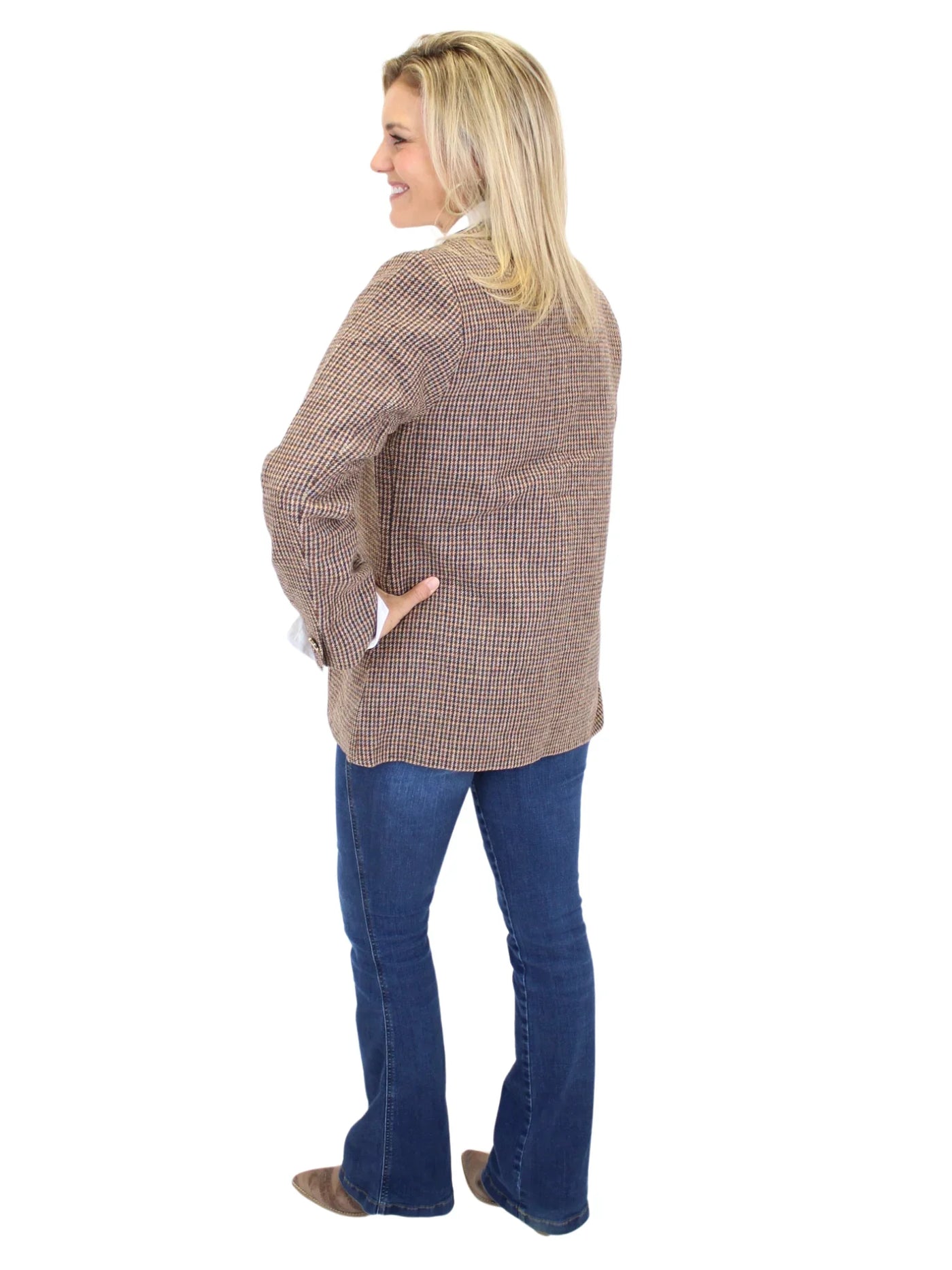 Woman wearing a brown plaid blazer and blue jeans on a white background, back.