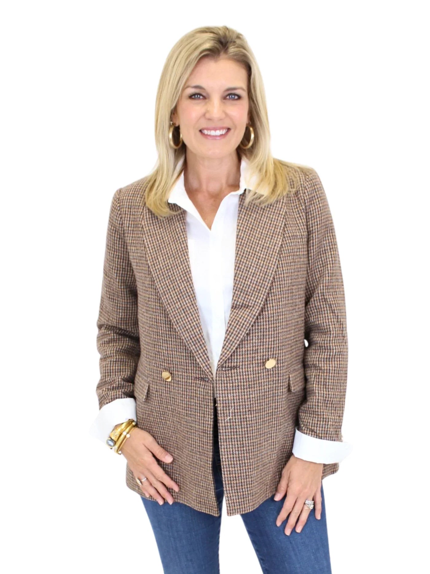 Woman wearing a brown plaid blazer with gold buttons on a white background, closeup front.