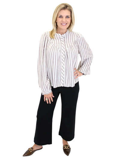 Woman wearing a white and black striped shirt with black pants on a white background, front.