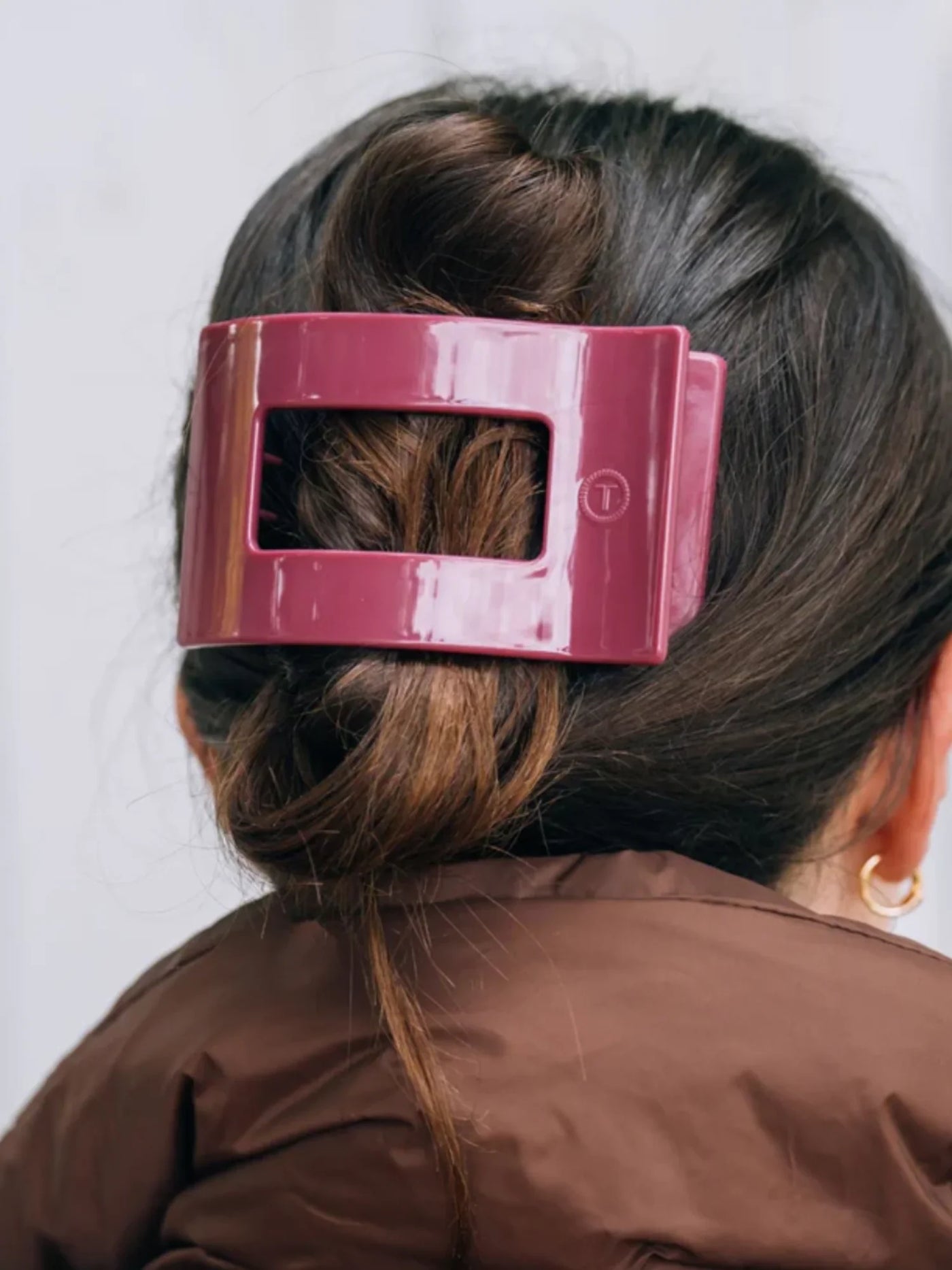 Maroon large rectangle hair clip on woman's hair.